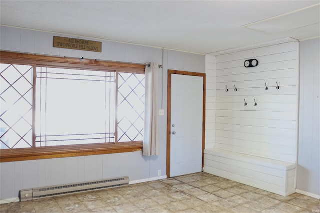 interior space featuring a baseboard heating unit, a healthy amount of sunlight, and wood walls