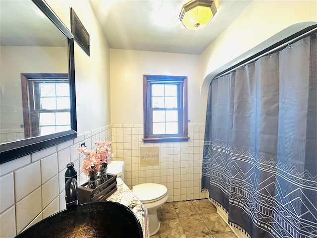 bathroom with tile walls, tile patterned floors, and toilet