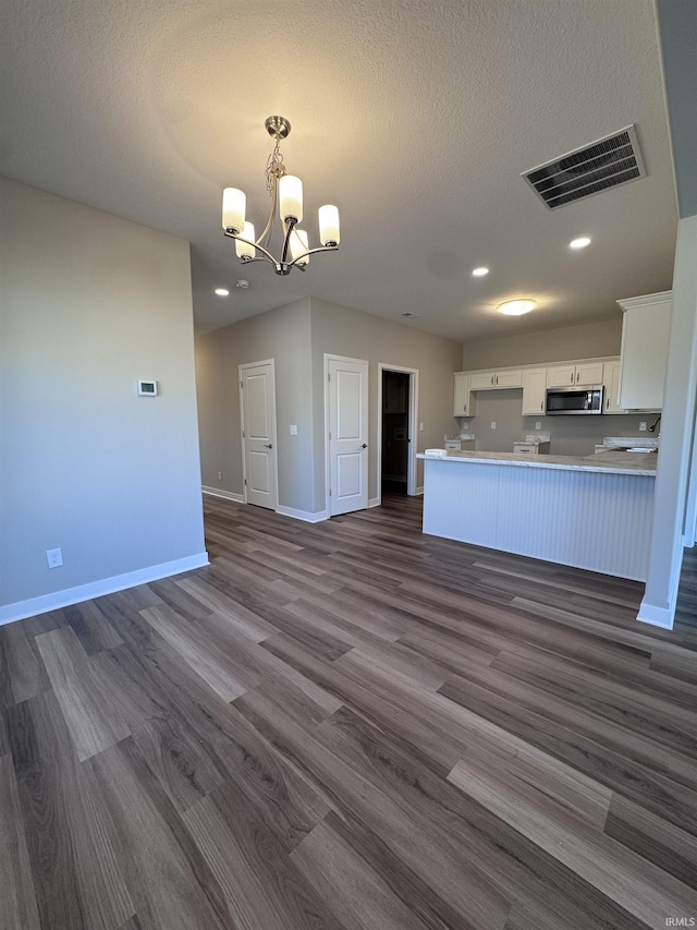 kitchen featuring visible vents, dark wood finished floors, stainless steel microwave, open floor plan, and an inviting chandelier