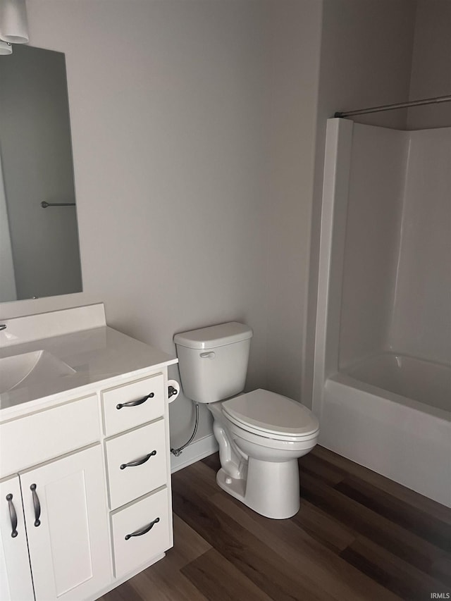 bathroom with vanity, wood finished floors, toilet, baseboards, and shower / bath combination