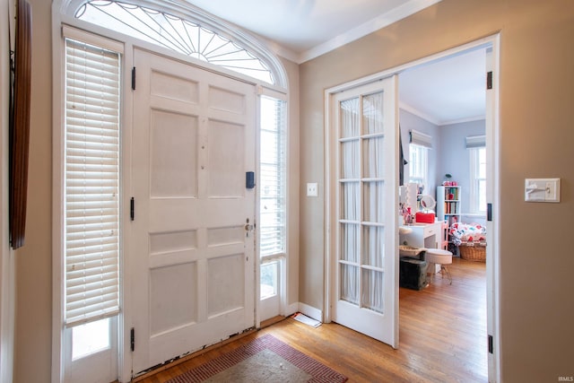 foyer entrance with a wealth of natural light, ornamental molding, and light hardwood / wood-style floors