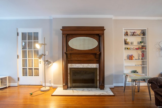 sitting room featuring crown molding, hardwood / wood-style floors, built in shelves, and a premium fireplace