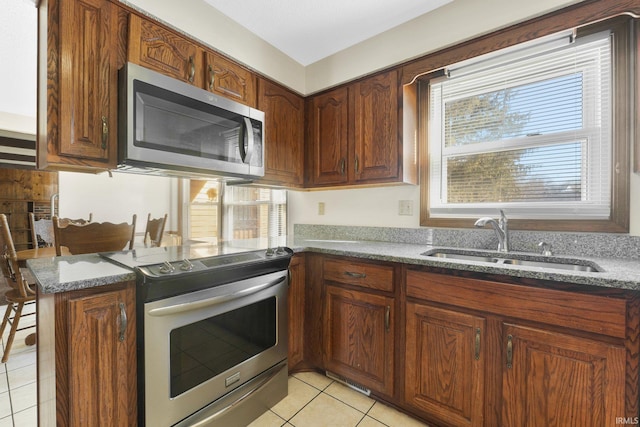 kitchen featuring light tile patterned flooring, stainless steel appliances, kitchen peninsula, and sink