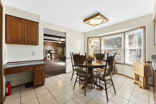 dining area with wood walls, a brick fireplace, light carpet, and a textured ceiling