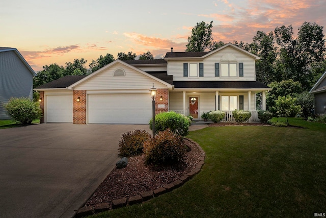 front of property with a garage, covered porch, and a lawn