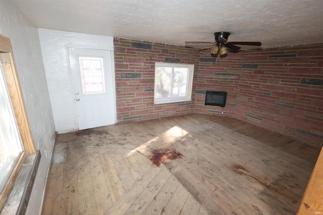 unfurnished living room featuring wood-type flooring, a textured ceiling, and ceiling fan