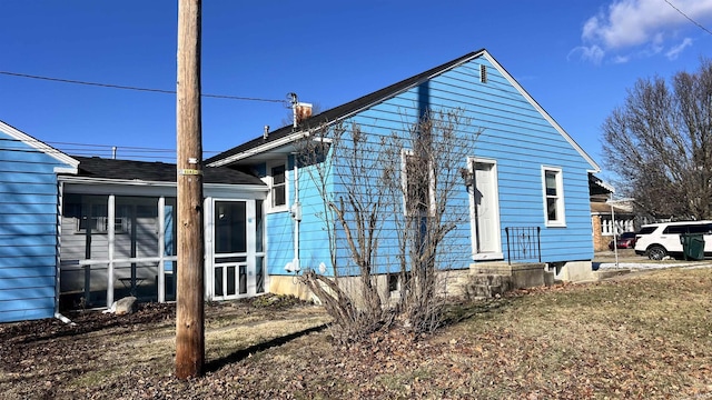 rear view of property with a lawn and a sunroom