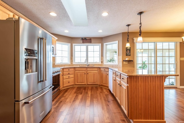 kitchen with sink, light brown cabinets, premium appliances, and kitchen peninsula