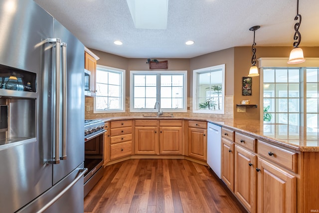 kitchen with decorative light fixtures, sink, decorative backsplash, and stainless steel appliances