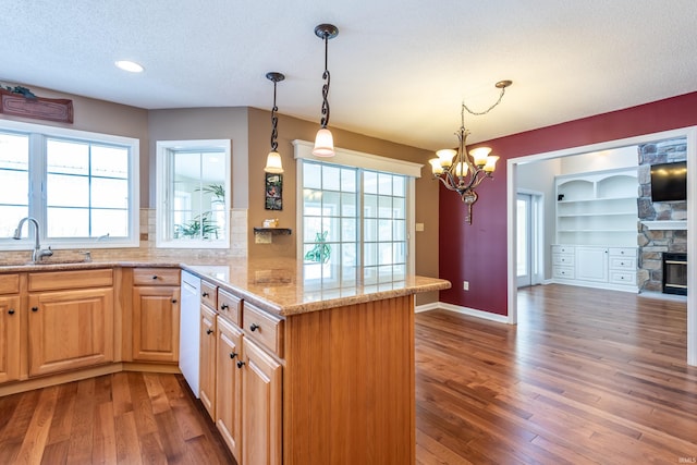 kitchen featuring tasteful backsplash, light stone countertops, sink, and kitchen peninsula