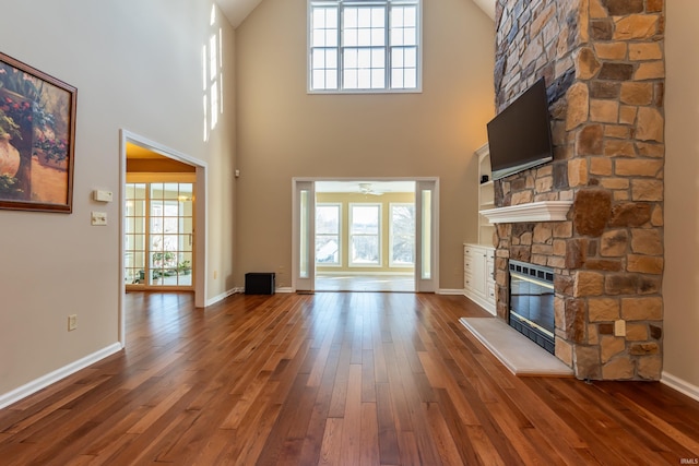 unfurnished living room with hardwood / wood-style flooring, a fireplace, and a high ceiling