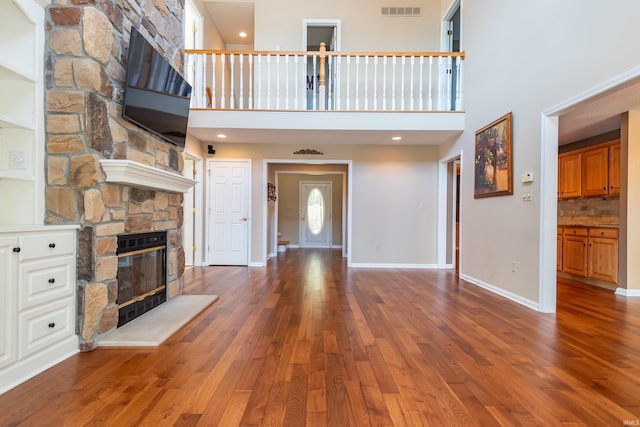 unfurnished living room with a fireplace, hardwood / wood-style floors, and a high ceiling