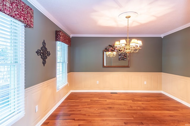 unfurnished dining area featuring ornamental molding, an inviting chandelier, and light hardwood / wood-style floors