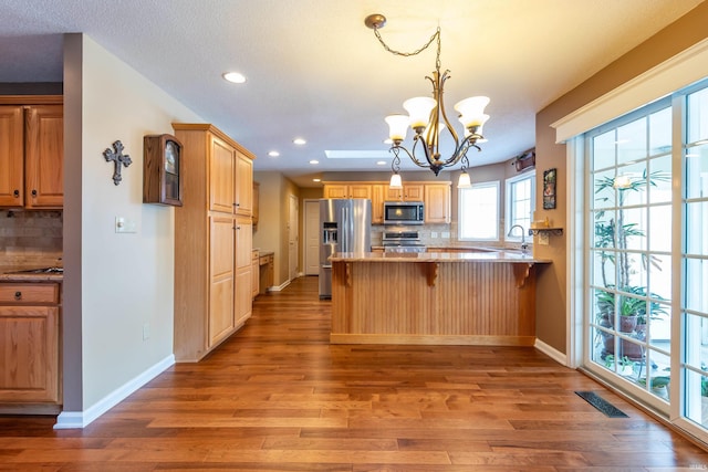 kitchen featuring decorative backsplash, appliances with stainless steel finishes, a breakfast bar, and kitchen peninsula