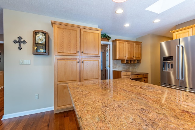 kitchen with a skylight, tasteful backsplash, high end refrigerator, dark wood-type flooring, and a textured ceiling