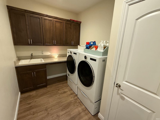 laundry area featuring cabinets, sink, washer and clothes dryer, and light hardwood / wood-style floors