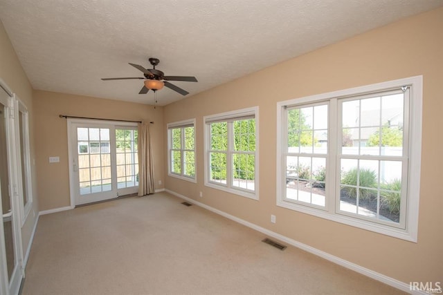 spare room with ceiling fan, light carpet, and a textured ceiling