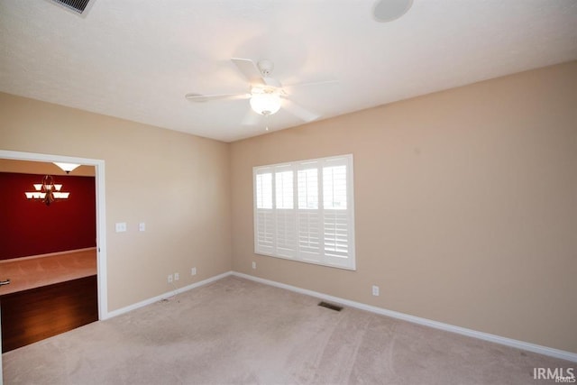 carpeted empty room with ceiling fan with notable chandelier