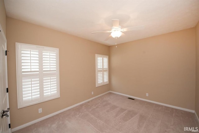 spare room with light carpet, a wealth of natural light, and ceiling fan