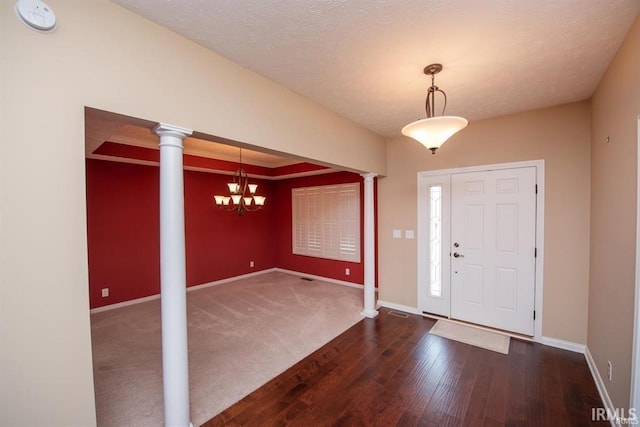 foyer with dark hardwood / wood-style flooring, a chandelier, and ornate columns