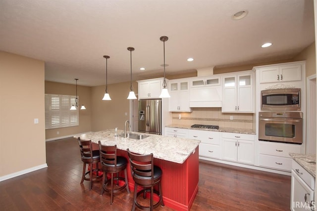 kitchen featuring a kitchen island with sink, sink, pendant lighting, and appliances with stainless steel finishes