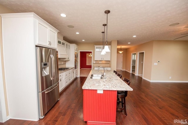 kitchen featuring decorative light fixtures, white cabinetry, a breakfast bar area, a large island, and stainless steel appliances