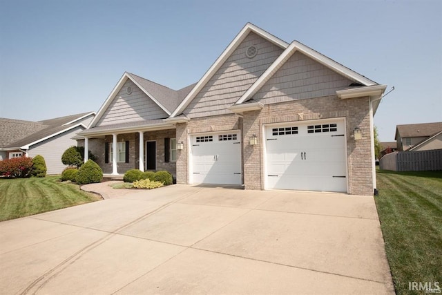 craftsman inspired home featuring a porch, a garage, and a front lawn