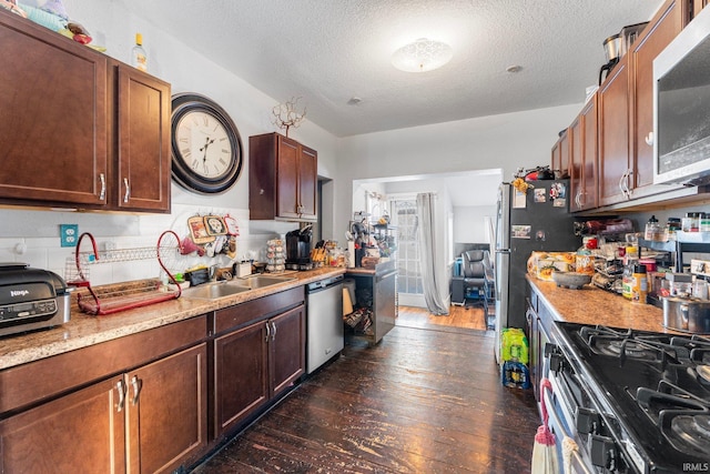 kitchen featuring sink, appliances with stainless steel finishes, light stone counters, a textured ceiling, and dark hardwood / wood-style flooring