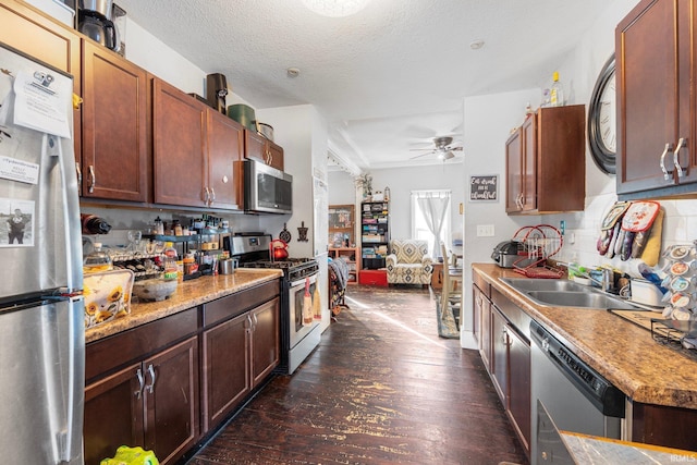 kitchen featuring sink, ceiling fan, stainless steel appliances, a textured ceiling, and dark hardwood / wood-style flooring