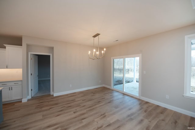 unfurnished dining area with a chandelier and light wood-type flooring