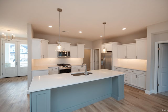 kitchen featuring appliances with stainless steel finishes, decorative light fixtures, sink, and white cabinets