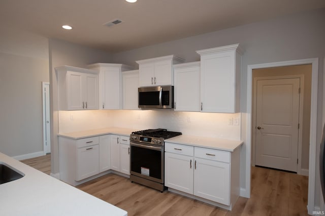 kitchen with appliances with stainless steel finishes, white cabinets, and decorative backsplash