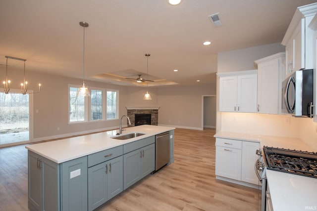 kitchen featuring white cabinetry, appliances with stainless steel finishes, a fireplace, and sink