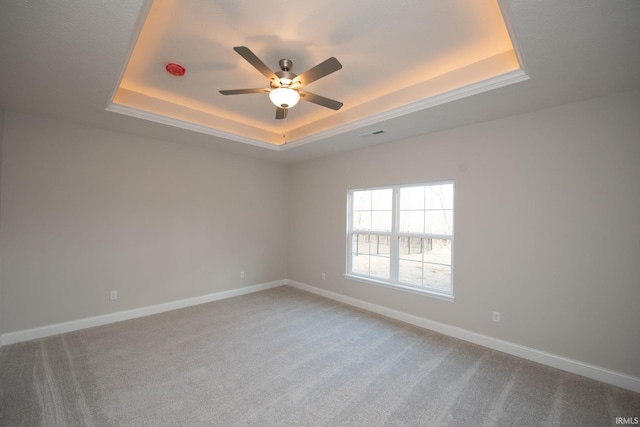 empty room featuring carpet flooring, ceiling fan, and a tray ceiling