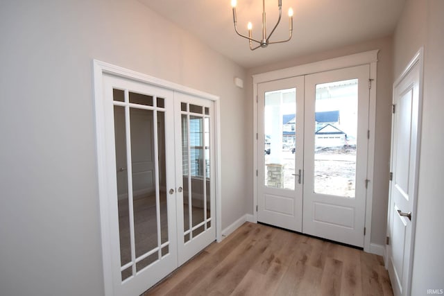 entryway with light hardwood / wood-style flooring, french doors, and a chandelier