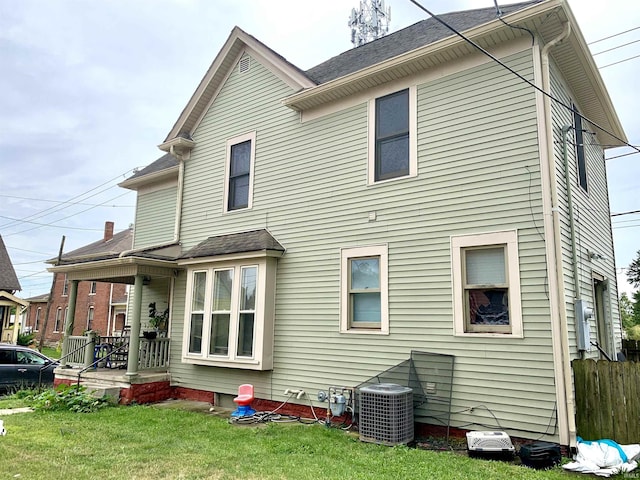 rear view of property with a yard and central AC unit