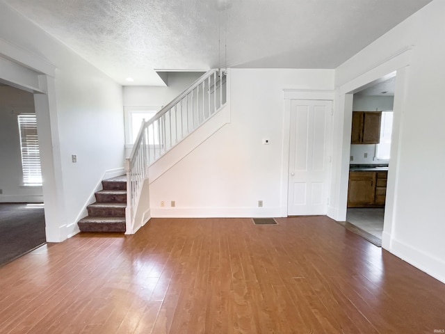 unfurnished living room with hardwood / wood-style flooring and a textured ceiling