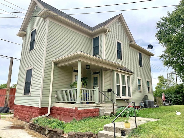 view of front of property featuring cooling unit, covered porch, and a front lawn