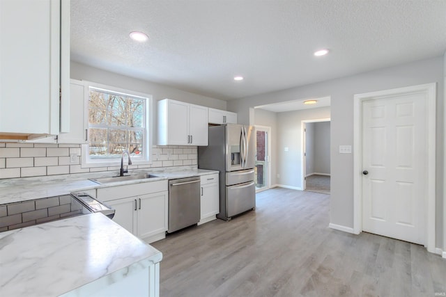 kitchen with appliances with stainless steel finishes, sink, white cabinets, backsplash, and a textured ceiling