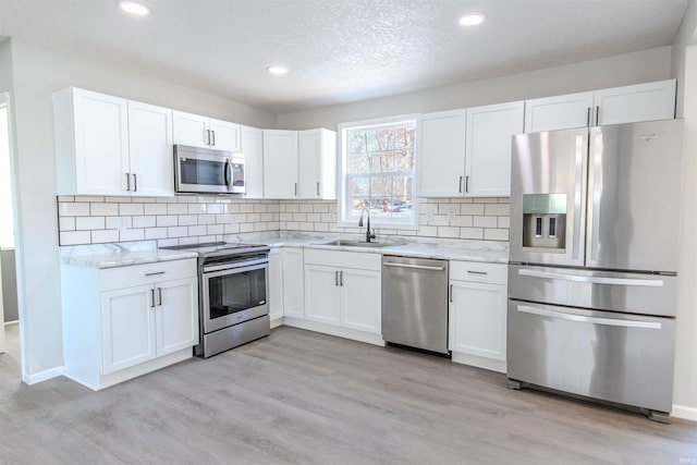 kitchen featuring sink, stainless steel appliances, white cabinets, and light stone countertops