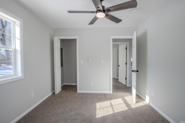 unfurnished bedroom with a textured ceiling, light colored carpet, and ceiling fan