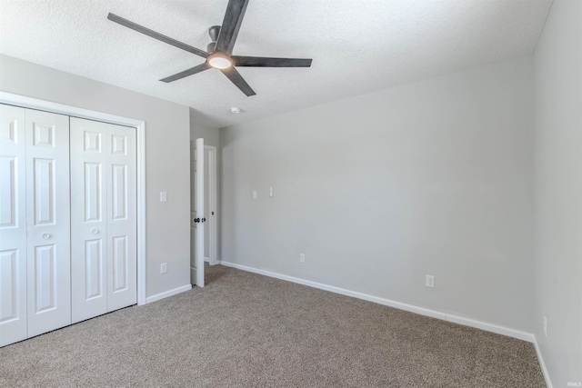 unfurnished bedroom with a textured ceiling, a closet, ceiling fan, and carpet