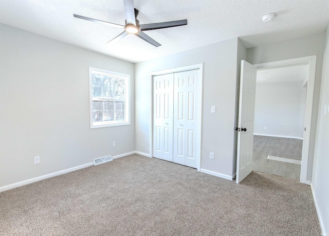 unfurnished bedroom with ceiling fan, carpet floors, a closet, and a textured ceiling