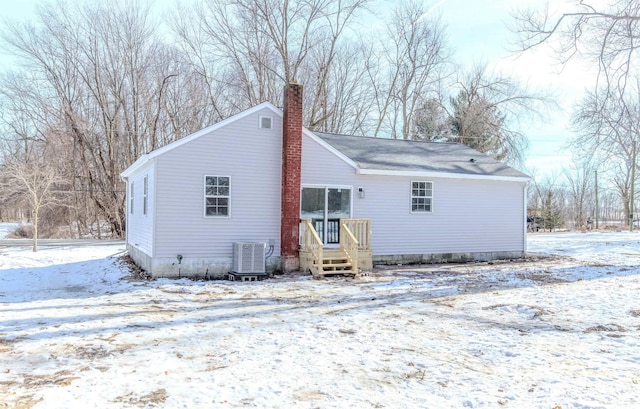 snow covered back of property with central AC