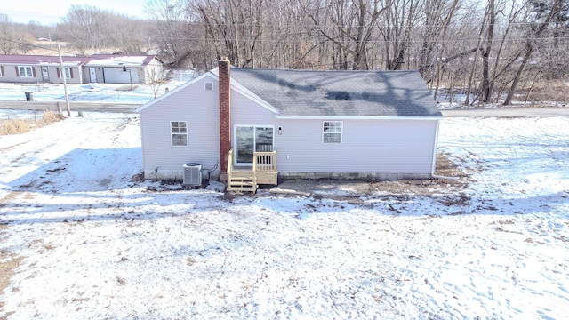 snow covered rear of property featuring central AC unit