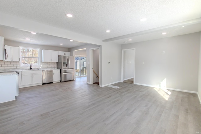 unfurnished living room featuring sink, a textured ceiling, and light wood-type flooring