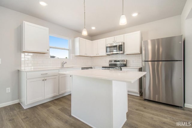 kitchen featuring hanging light fixtures, appliances with stainless steel finishes, and white cabinets