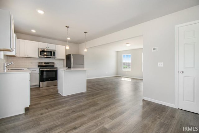 kitchen with white cabinetry, stainless steel appliances, decorative light fixtures, and a center island