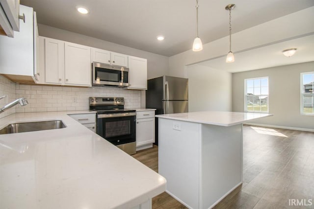 kitchen with stainless steel appliances, a kitchen island, sink, and hanging light fixtures