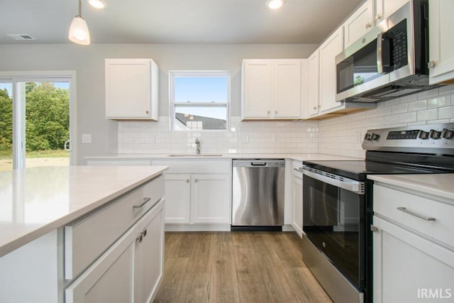 kitchen with pendant lighting, sink, white cabinets, and appliances with stainless steel finishes